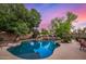 Inviting freeform pool with rock features, surrounded by mature trees and lush landscaping at 1201 W Washington Ave, Gilbert, AZ 85233