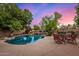 Inviting freeform pool with rock features, surrounded by mature trees and lush landscaping at 1201 W Washington Ave, Gilbert, AZ 85233