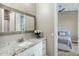 Well-lit bathroom with granite counters, white cabinets, and a decorative mirror with a view to another bedroom at 19575 E Vallejo St, Queen Creek, AZ 85142