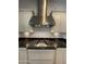 Close-up view of the kitchen cooktop, stainless steel vent hood and attractive cabinetry with granite countertops at 4142 E Zion Pl, Chandler, AZ 85249