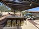 Outdoor kitchen and patio area with a built-in grill, bar seating, and view of a sparkling pool with mature landscaping at 4142 E Zion Pl, Chandler, AZ 85249