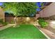 Lush backyard featuring artificial turf, mature trees, and landscape lighting, creating a serene outdoor retreat at 3129 S Honeysuckle Ct, Gold Canyon, AZ 85118