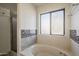 Bathroom featuring a soaking tub, shower and horizontal tile accent at 5249 E Hobart St, Mesa, AZ 85205