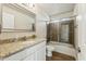 A bathroom features granite countertop, glass enclosed tub and plank flooring at 31812 N 221St Dr, Wittmann, AZ 85361