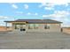 Back view of a single-story tan home with a brown roof, a covered patio, and large glass windows and sliding doors at 31824 N 221St Dr, Wittmann, AZ 85361