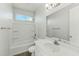 Bright bathroom featuring a single sink vanity, tub/shower combo, and a window for natural light at 31824 N 221St Dr, Wittmann, AZ 85361