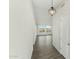 The hallway features grey wood-look flooring, white walls, a pendant light, and a view of the outdoors through windows at 31824 N 221St Dr, Wittmann, AZ 85361