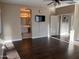 Open-concept bedroom with wood floors leads to ensuite bathroom and features ceiling fan and wall-mounted television at 44449 W Canyon Creek Dr, Maricopa, AZ 85139