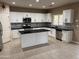 Bright kitchen featuring white cabinets, stainless steel appliances, dark countertops and a central island at 44449 W Canyon Creek Dr, Maricopa, AZ 85139