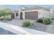 Tan house with brown garage door, landscaping, and a paved driveway at 27002 W Oraibi Dr, Buckeye, AZ 85396