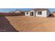View of the dirt backyard with privacy fence and new home construction beyond at 11937 W Parkway Ln, Avondale, AZ 85323
