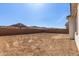 View of a large dirt backyard with a block wall fence and several homes in the distance at 11937 W Parkway Ln, Avondale, AZ 85323