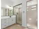Bright bathroom features double sinks, white cabinetry, and a glass-enclosed shower with beige tile at 11937 W Parkway Ln, Avondale, AZ 85323