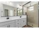 Bright bathroom features double sinks, white cabinetry, and a glass-enclosed shower with beige tile at 11937 W Parkway Ln, Avondale, AZ 85323