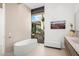 Modern bathroom features a soaking tub, sleek vanity, and a window offering views of cacti and desert scenery at 4301 E Upper Ridge Way, Paradise Valley, AZ 85253