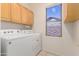 Convenient laundry room features a washer, dryer, upper cabinets, and a window for natural light at 1451 E Palm Beach Dr, Chandler, AZ 85249