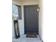 Charming front entryway featuring a black door, welcome sign, decorative mat, and a warm lantern at 23200 W Ashleigh Marie Dr, Buckeye, AZ 85326