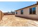 View of the back of the house showing dirt lot backyard space, block wall, and windows at 12333 W Marguerite Ave, Avondale, AZ 85323