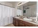 Bathroom features a double sink vanity with decorative mirror and a white shower curtain at 18147 W Ida Ln, Surprise, AZ 85387