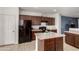 Kitchen featuring dark cabinets, a black refrigerator, tiled floors, and a central island with a speckled countertop at 18147 W Ida Ln, Surprise, AZ 85387
