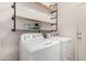 Practical laundry room with front-load washer and dryer, plus decorative storage shelves at 18147 W Ida Ln, Surprise, AZ 85387