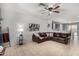 A living room featuring a leather sectional, ceiling fan and open access to the kitchen at 18147 W Ida Ln, Surprise, AZ 85387
