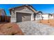Attached two-car garage with a paved driveway, stone accents, gray trim, and desert landscaping at 5338 W Manzanita Dr, Glendale, AZ 85302