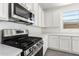 Close-up of the gourmet kitchen with stainless steel gas range, microwave, and white cabinets at 12326 W Marguerite Ave, Avondale, AZ 85323