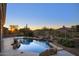 A backyard pool with a rock feature and lush greenery, perfect for outdoor relaxation and entertainment at 11566 E Christmas Cholla Dr, Scottsdale, AZ 85255