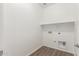Compact laundry room with wood-look flooring and open shelf for storage solutions at 12330 W Marguerite Ave, Avondale, AZ 85323