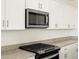 Close up of granite counters, white cabinets, stainless microwave, and black gas range at 3649 E Alexander Dr, San Tan Valley, AZ 85143
