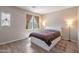 Well-lit bedroom featuring a bed with storage, complemented by wood-look flooring and windows with decorative curtains at 35202 N 30Th Dr, Phoenix, AZ 85086