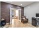 Home office featuring a brick accent wall, tiled floors, and patio access through double doors to the backyard at 35202 N 30Th Dr, Phoenix, AZ 85086