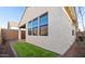 Exterior view of the backyard with well-maintained stucco wall, artificial turf and multiple windows at 4430 N 203Rd Dr, Buckeye, AZ 85396