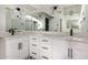 A bathroom vanity features dual sinks, white cabinets, black hardware, and decorative mirrors and light fixtures at 11035 E Clinton St, Scottsdale, AZ 85259
