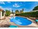 An inground kidney shaped pool features a new pool cleaner and is surrounded by mature landscaping at 11035 E Clinton St, Scottsdale, AZ 85259