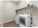 This laundry room features white appliances, gray walls, and shelving for storage at 2229 N Beverly Pl, Buckeye, AZ 85396