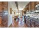 Gourmet kitchen with dark wood cabinets, stainless steel appliances, and rustic tile flooring flowing into the dining area at 7002 N Hillside Dr, Paradise Valley, AZ 85253