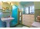 Bathroom with mint green tile, pedestal sink, shower, and built-in drawers at 363 E Monte Vista Rd, Phoenix, AZ 85004