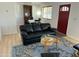 Cozy living room with hardwood floors, a black sofa, and a decorative blue rug at 2752 W Lawrence Rd, Phoenix, AZ 85017