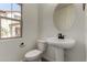 Modern half bath features white fixtures, a pedestal sink, and a stylish oval mirror at 2878 N Evergreen St, Buckeye, AZ 85396