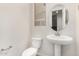 Bright powder room featuring a pedestal sink, oval mirror, toilet, and a small window at 2888 N Evergreen St, Buckeye, AZ 85396