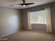 Neutral bedroom with a ceiling fan, carpeted floor, and window with bright light and privacy blinds at 12956 W El Sueno Ct, Sun City West, AZ 85375