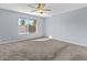 Spacious bedroom featuring plush carpeting, a ceiling fan, and a bright window view at 2409 E Hampton Ave, Mesa, AZ 85204