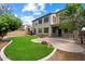 Spacious backyard with lush green lawn, a brick patio, mature trees, and the home's exterior at 1392 E Baker Dr, San Tan Valley, AZ 85140