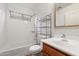 Well-lit bathroom with a shower-tub combo, storage shelves, a large mirror, and a single sink at 1392 E Baker Dr, San Tan Valley, AZ 85140