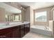 Bathroom features a soaking tub, a walk-in shower and dual sinks with a large mirror at 272 N 167Th Ln, Goodyear, AZ 85338