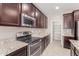 Kitchen features stainless steel appliances, granite countertops, a pantry and dark wood cabinets at 272 N 167Th Ln, Goodyear, AZ 85338