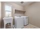Functional laundry room featuring a utility sink, overhead shelving, and modern washer and dryer at 272 N 167Th Ln, Goodyear, AZ 85338