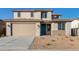 Two-story house with tan exterior, teal door, and landscaped yard at 18424 W Monte Lindo Ln, Surprise, AZ 85387